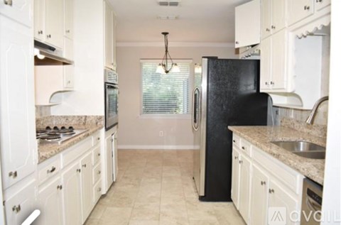 A kitchen with black fridge and white cabinets.