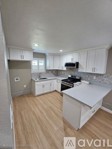 A kitchen with white cabinets and a wooden floor.