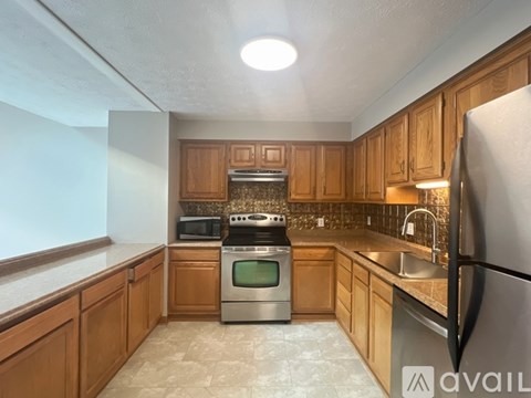 A kitchen with wooden cabinets and a stainless steel refrigerator.
