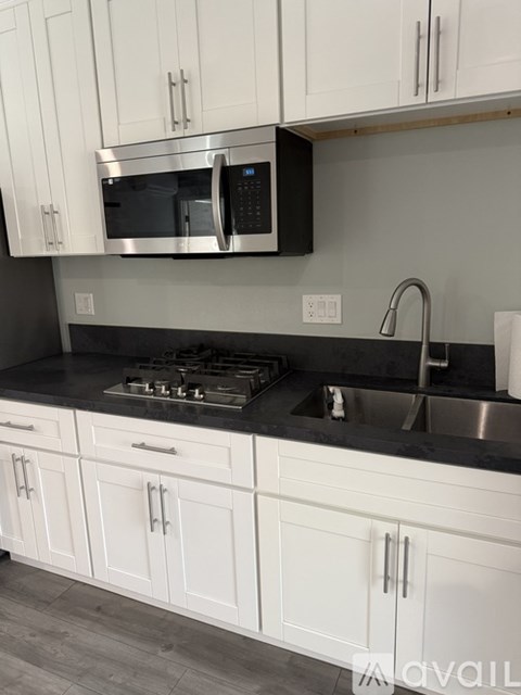 A kitchen with white cabinets and a black countertop.