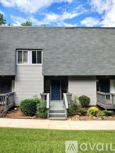 A grey house with a blue door and a small garden in front.