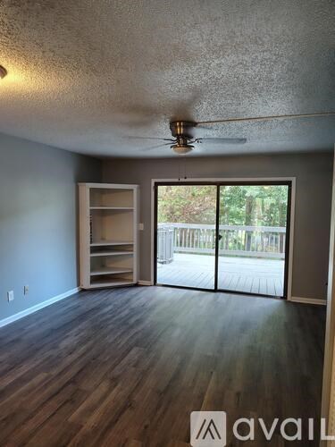 A room with a ceiling fan and sliding glass doors leading to a balcony.