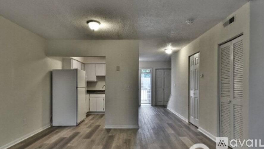 A room with a white fridge and wooden floors.
