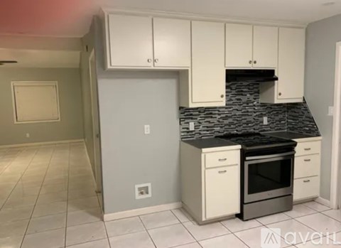 A kitchen with white cabinets and a black granite countertop.