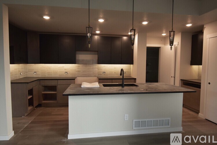 A modern kitchen with a center island and dark brown cabinets.