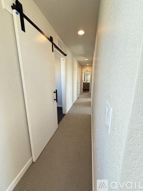 A hallway with a black door and a white wall.