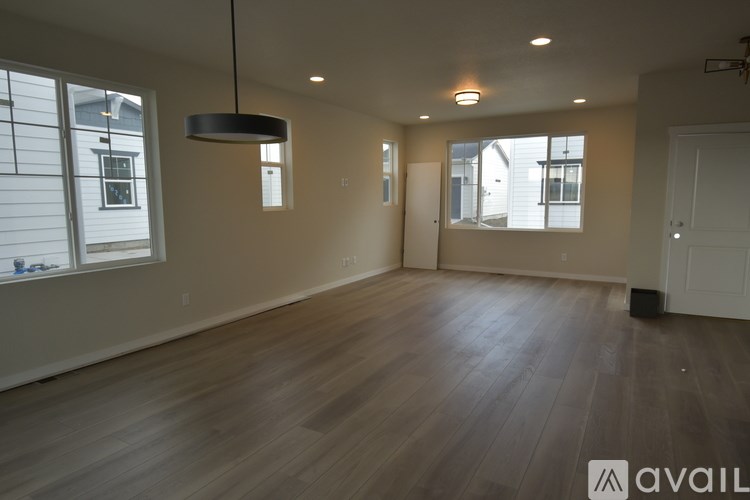 A spacious room with wooden flooring and a large window.