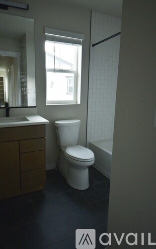 A white toilet sits in a bathroom next to a sink and a window.