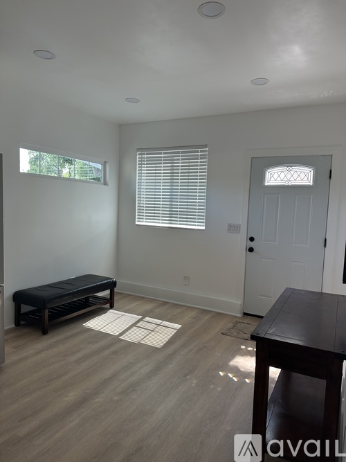 A room with a bench, table, and a door.