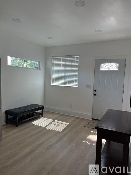 A room with a bench, table, and a door.