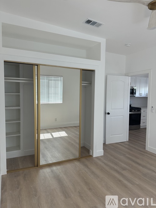 A room with a sliding door and a kitchen in the background.