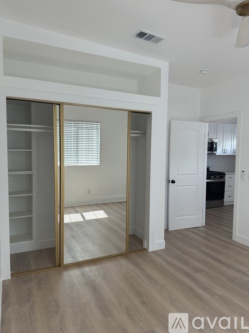 A room with a sliding door and a kitchen in the background.