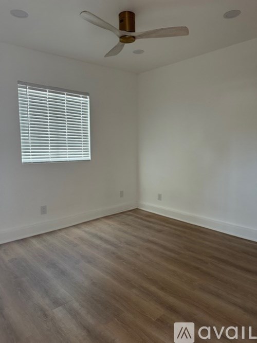 A room with a ceiling fan and a window with blinds.