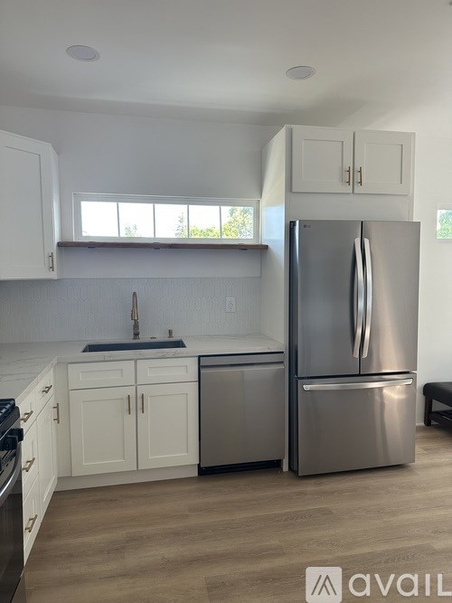 A modern kitchen with a stainless steel refrigerator and white cabinets.