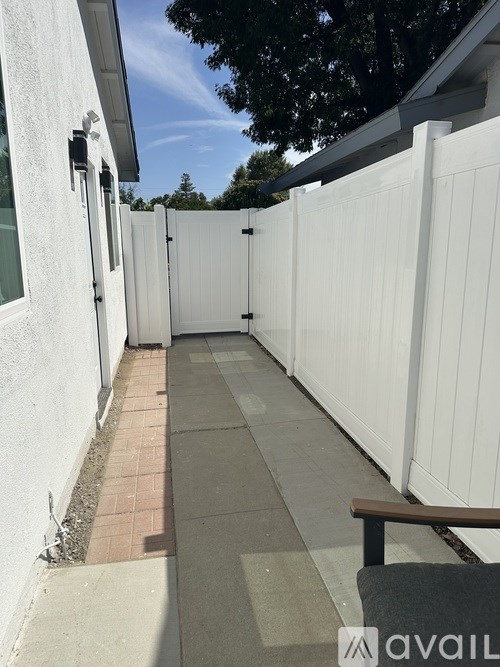 A white fence runs along the side of a house.