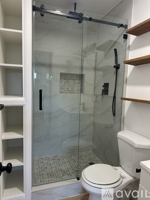 A white toilet in a bathroom with a walk-in shower.