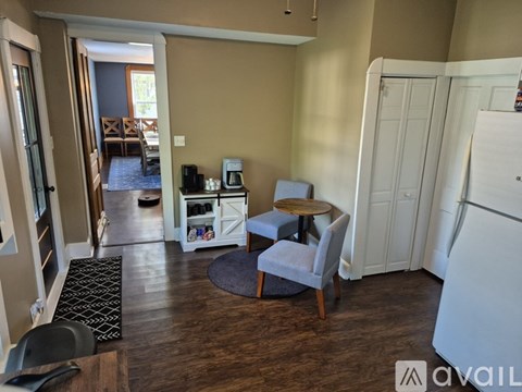 A kitchen area with a refrigerator, a table with a chair, and a coffee maker.