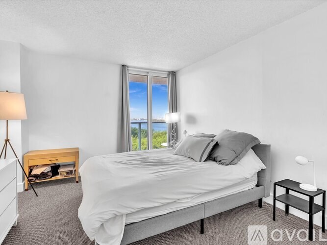 A bedroom with a large bed and a window overlooking the ocean.