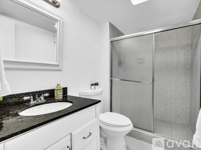 A modern bathroom with a sink, toilet, and shower.