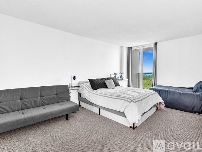 A bedroom with a large bed and a grey sofa.