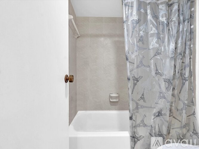 A white bathroom with a shower curtain featuring the Eiffel Tower.