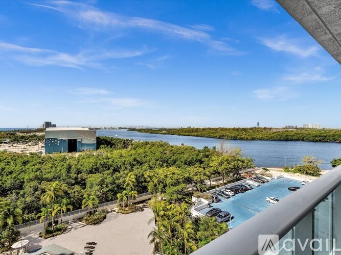 A view from a balcony overlooking a pool and a body of water with a building in the distance.