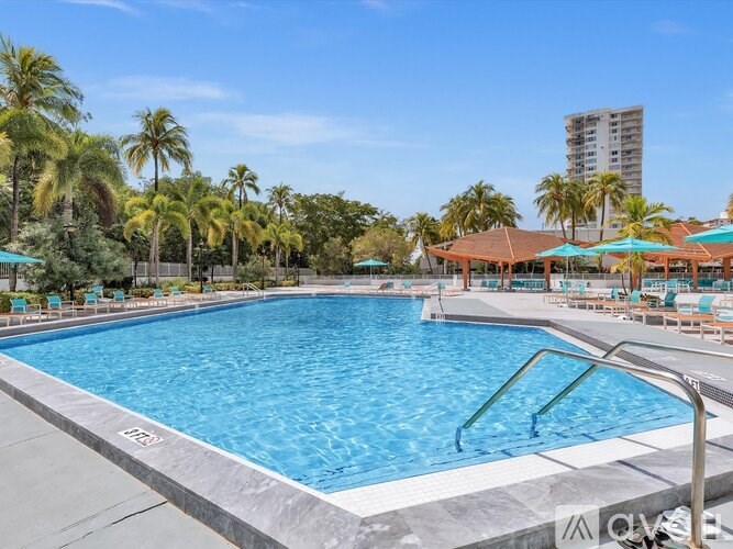 A large swimming pool surrounded by palm trees and lounge chairs.