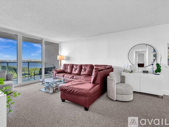 A living room with a red sofa and a round mirror on the wall.