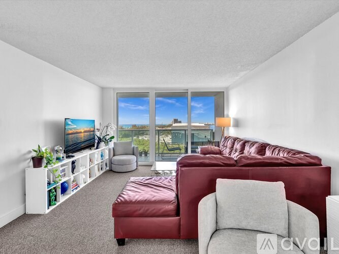 A living room with a red couch and a television on a white stand.