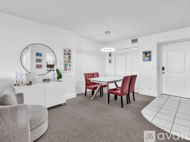 A dining room with a white table and red chairs.