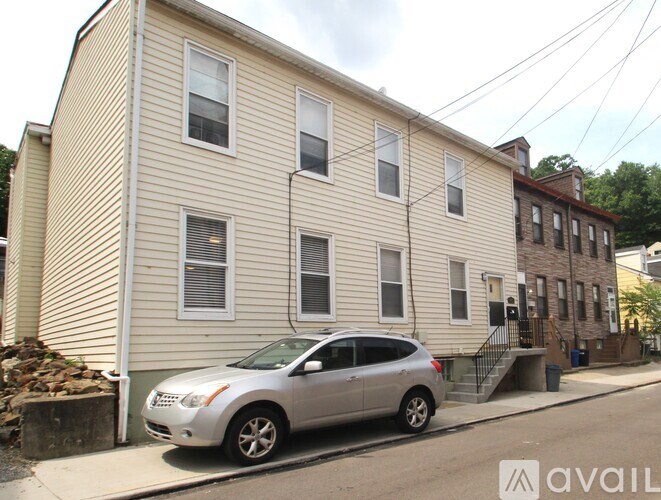 A silver car is parked in front of a house.