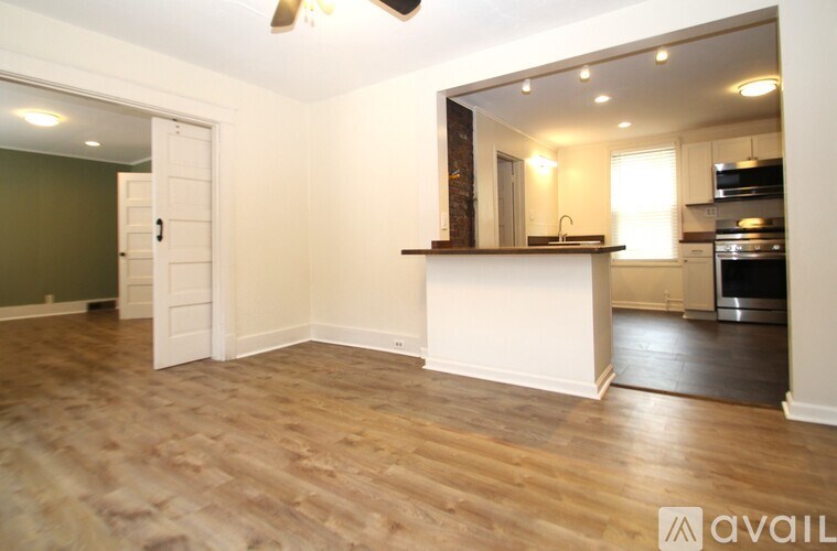 A spacious kitchen and living room with hardwood floors and a ceiling fan.