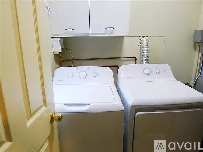 Two white washing machines are in a small room.