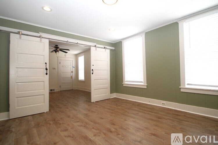 A room with a white door and a ceiling fan.
