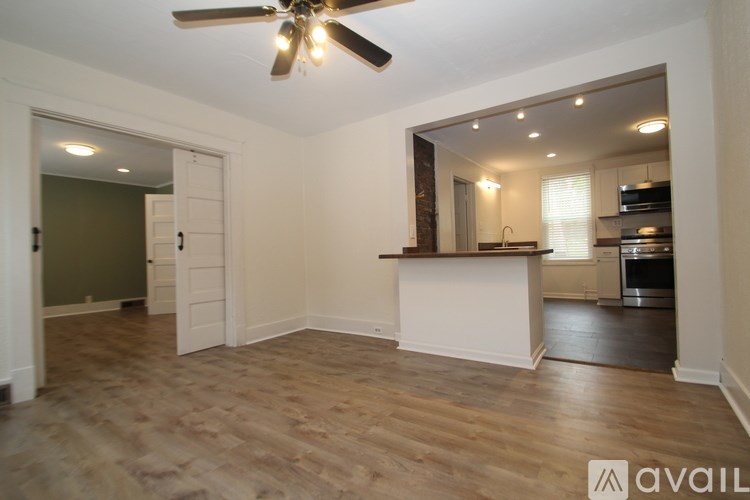 A spacious room with a ceiling fan and wooden flooring.