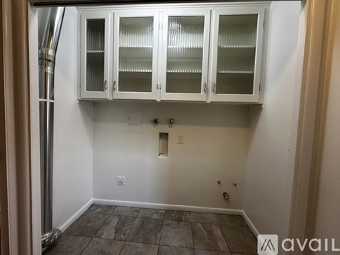 A kitchen area with white cabinets and a tiled floor.