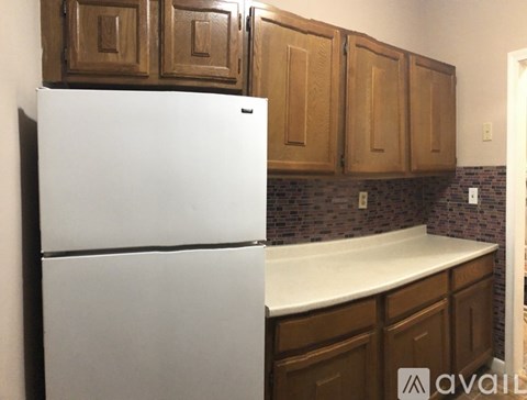 A white refrigerator in a kitchen with brown cabinets.