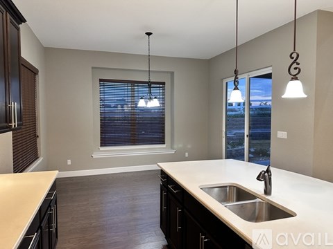 A kitchen with a sink and a window with blinds.