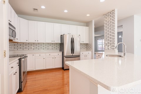 A kitchen with white cabinets and a brick wall.