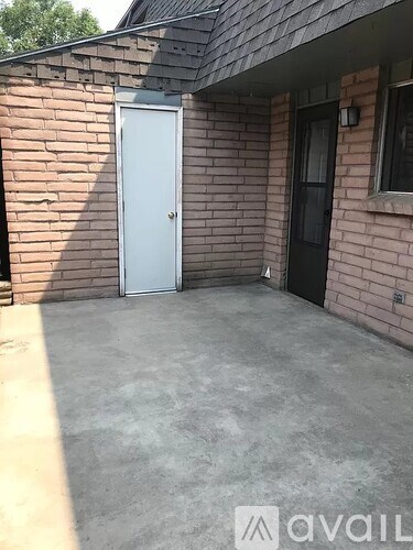 A white door is on the left side of a brick building.