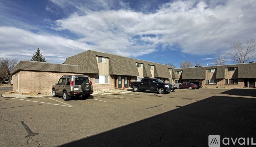 A parking lot with a building and cars parked in front.