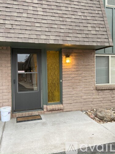 A house with a grey door and a window with a yellow curtain.