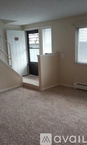 A carpeted room with a staircase and a window.