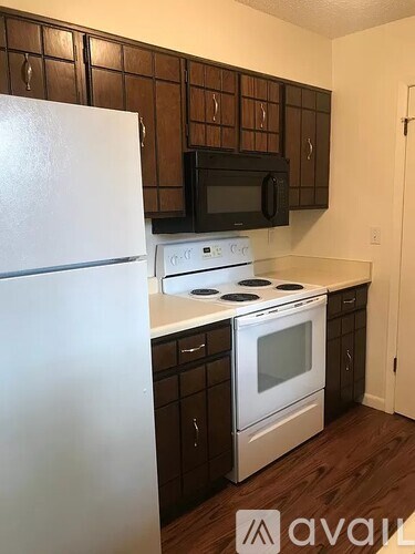 A kitchen with a white refrigerator, black microwave, and white stove top oven.