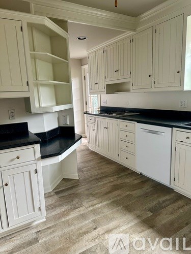 A kitchen with white cabinets and a black countertop.