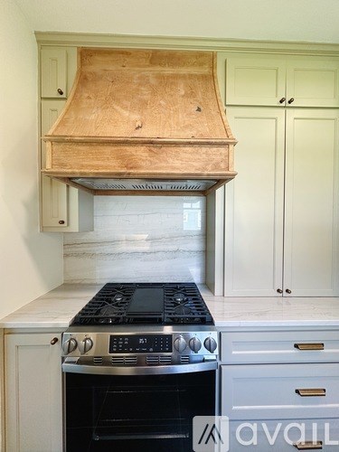 A kitchen with a stove top oven and a range hood.