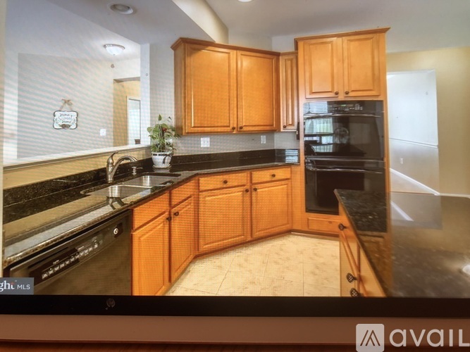 A kitchen with wooden cabinets and black countertops.