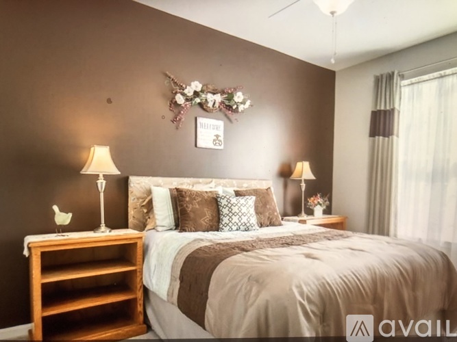 A bedroom with a bed, two lamps, and a decorative item on the wall.