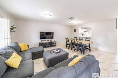 A living room with grey couches and yellow pillows.