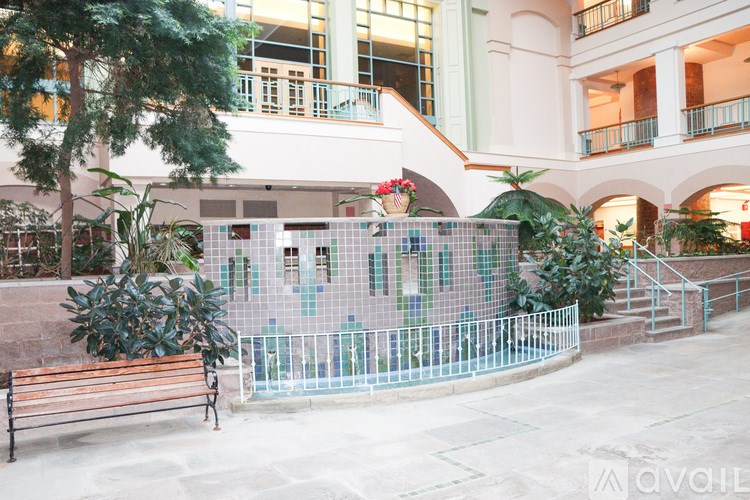 A bench is in front of a fence and a building.